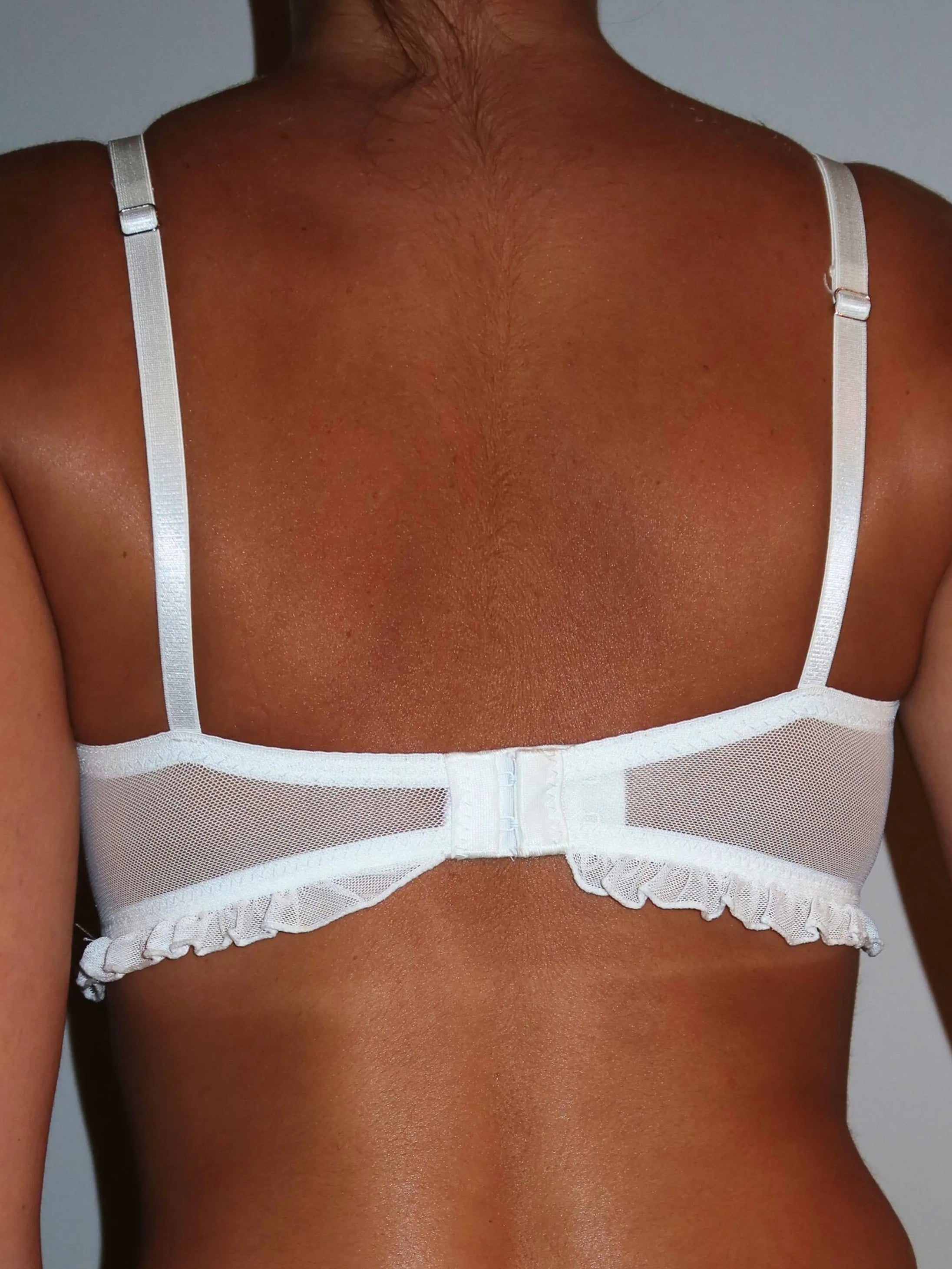 White lingerie set worn by a person on a plain background